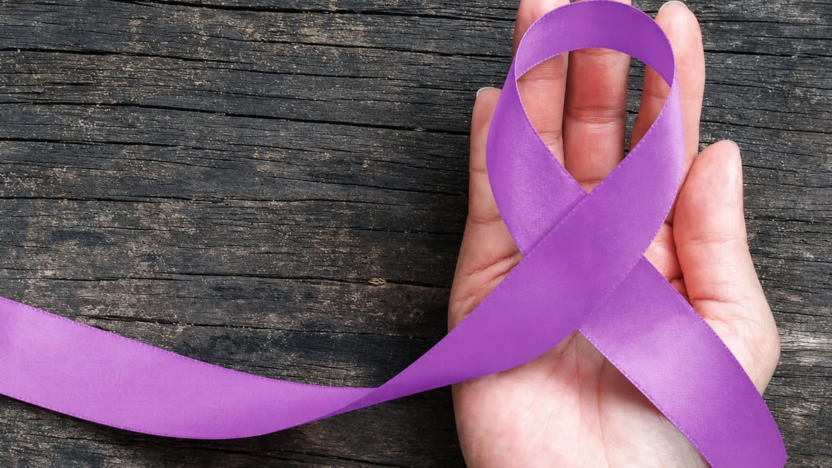 Un nastro viola tenuto in mano, simbolo delle campagne di sensibilizzazione